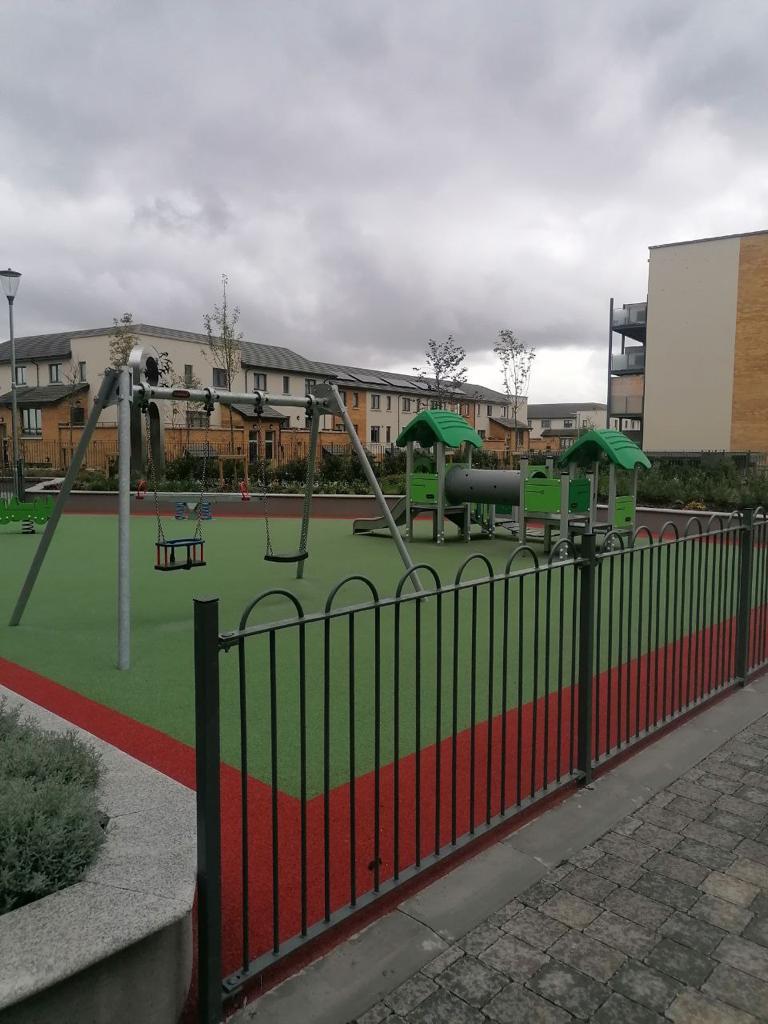 A playground with a slide, swings, and a jungle gym in a residential area.